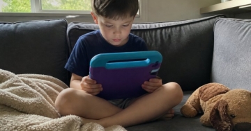Kind mit Tablet in Schutzhülle auf dem Sofa