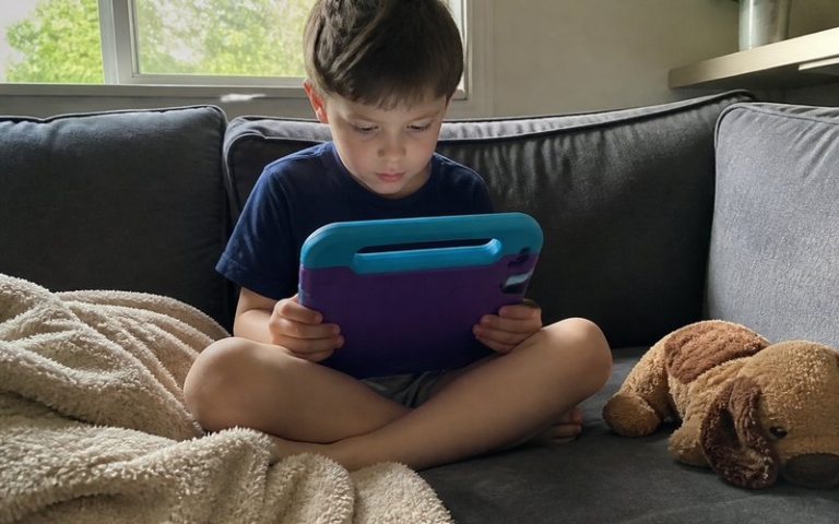 Kind mit Tablet in Schutzhülle auf dem Sofa
