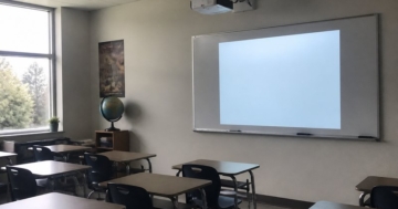 Beamer im Klassenzimmer über den Tischen